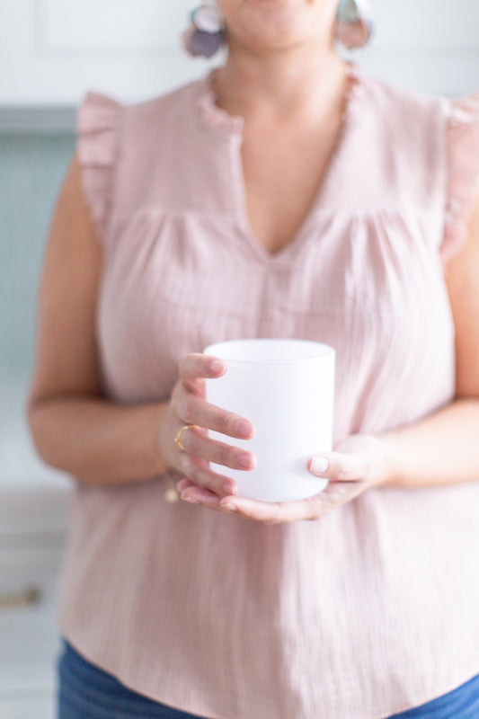 Close-up photograph of the maker holding a matte white Aura candle vessel